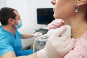 Clinician performing an ultrasound examination of the thyroid on a patient's neck